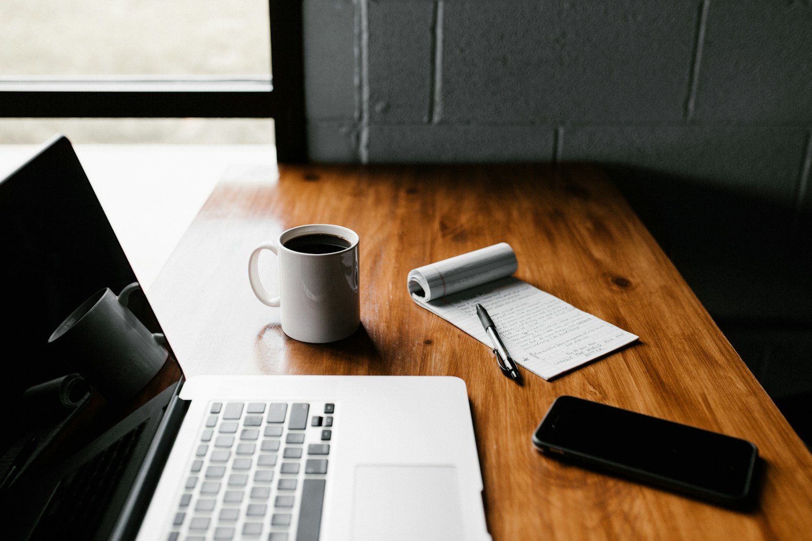 Home MacBook Pro, white ceramic mug,and black smartphone on table